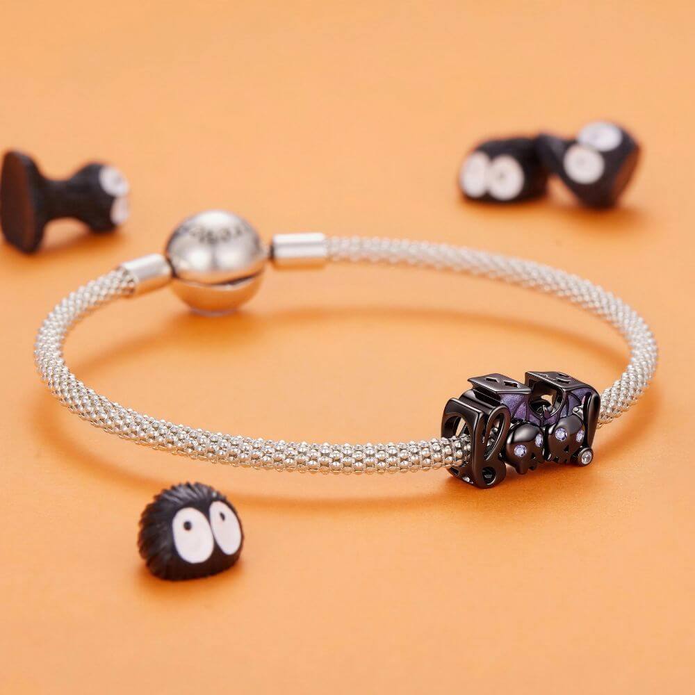Black skull and bat charm with purple crystal eyes, glitter wings, and playful spooky Halloween details.
