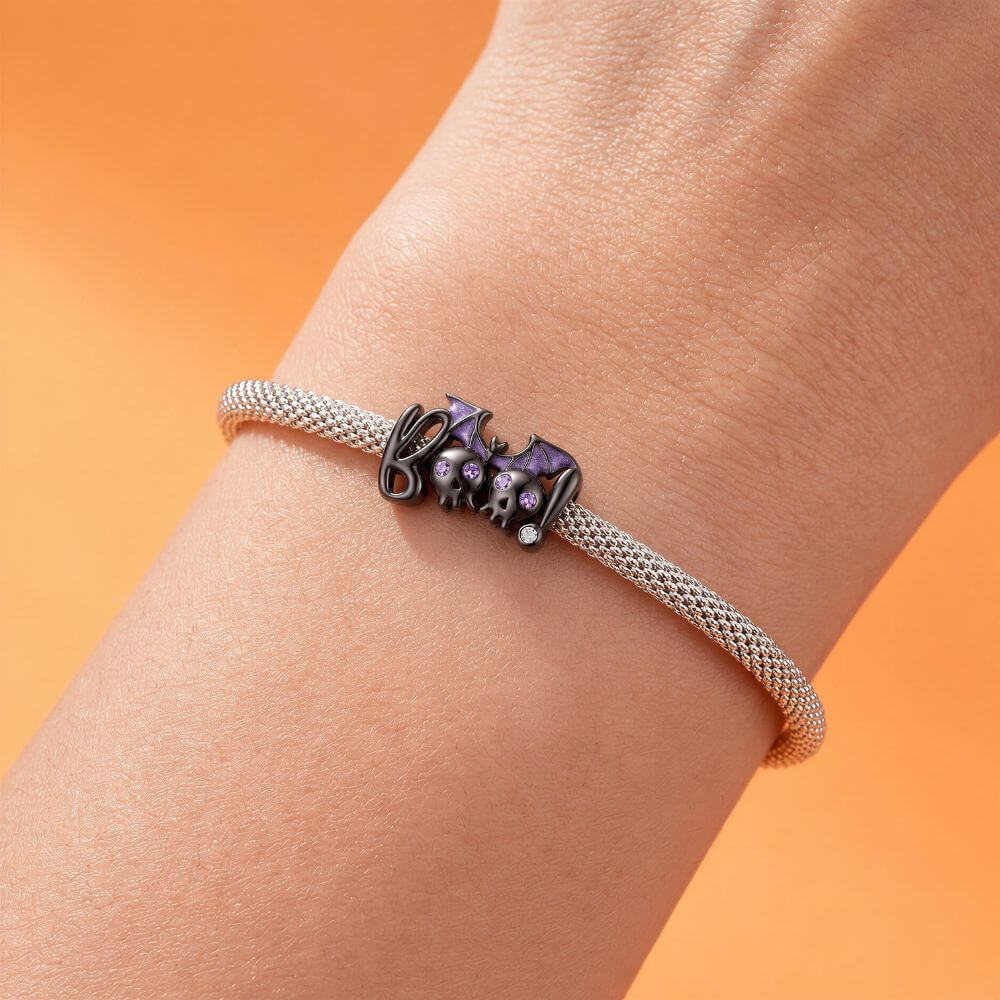 Black skull and bat charm with purple crystal eyes, glitter wings, and playful spooky Halloween details.