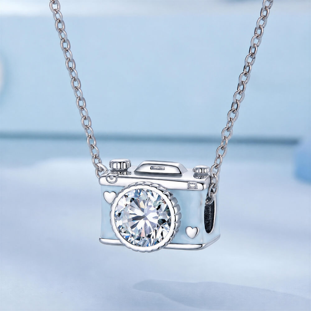 Sterling silver camera charm with blue enamel, heart details, and crystal lens.