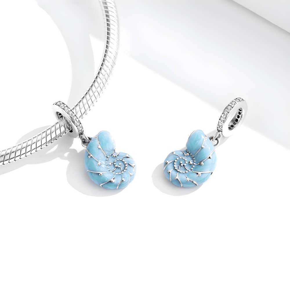 Sterling silver nautilus shell charm with blue enamel and clear gemstones.