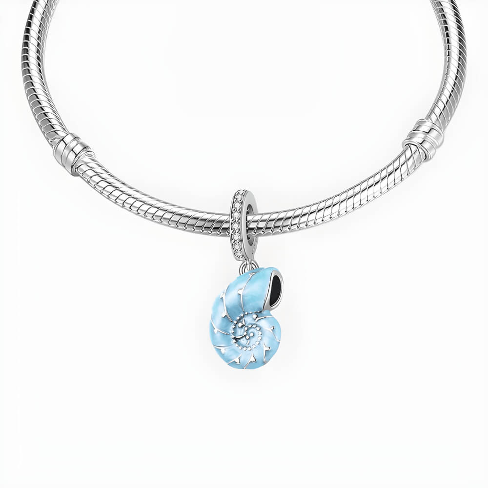 Sterling silver nautilus shell charm with blue enamel and clear gemstones.
