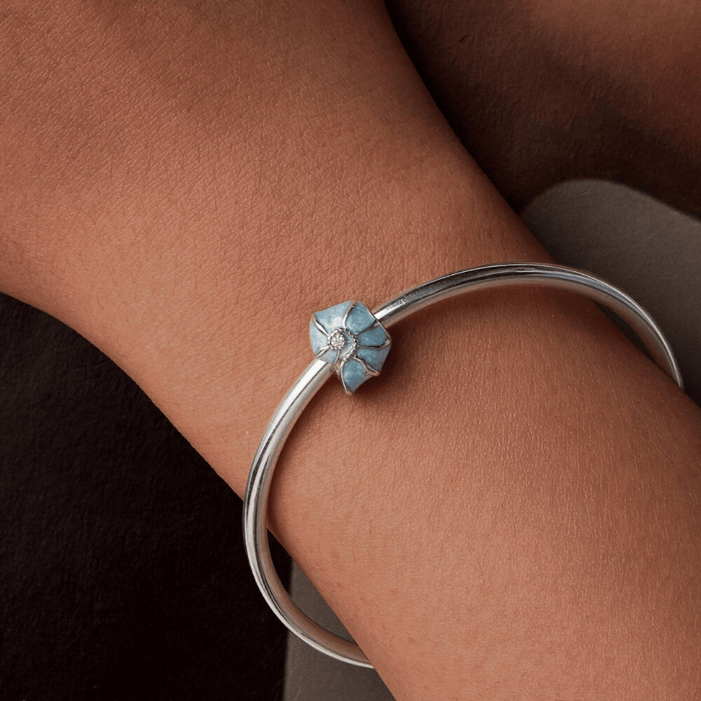 Sterling silver bead charm with blue enamel shell design and central clear gemstone.