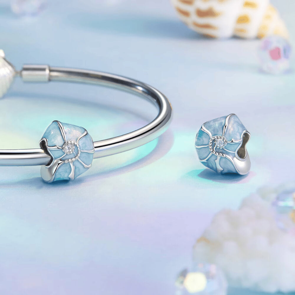 Sterling silver bead charm with blue enamel shell design and central clear gemstone.