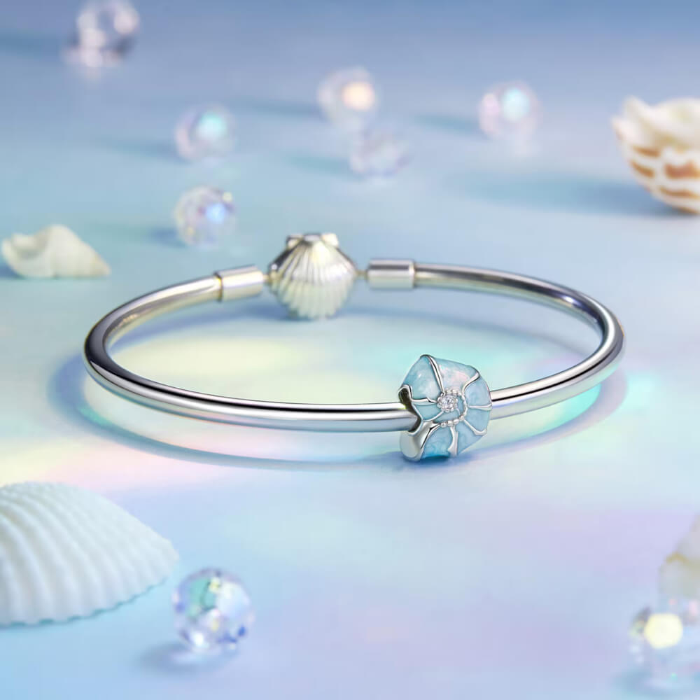 Sterling silver bead charm with blue enamel shell design and central clear gemstone.