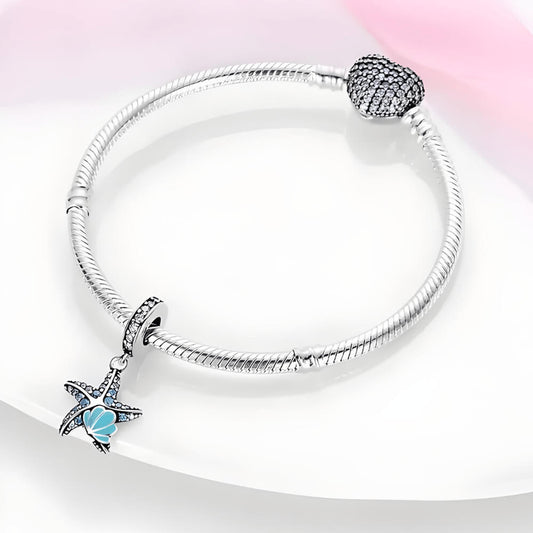 Sterling silver starfish charm with blue gemstones and teal enamel shell detail.