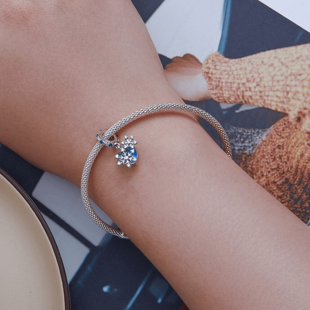 Sterling silver snowflake charm with blue heart crystal and blue gemstone bail.