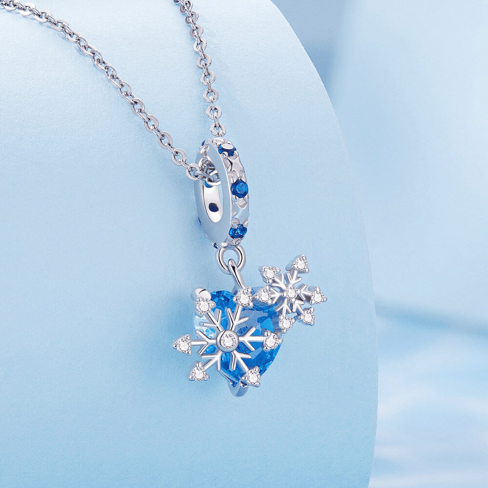 Sterling silver snowflake charm with blue heart crystal and blue gemstone bail.