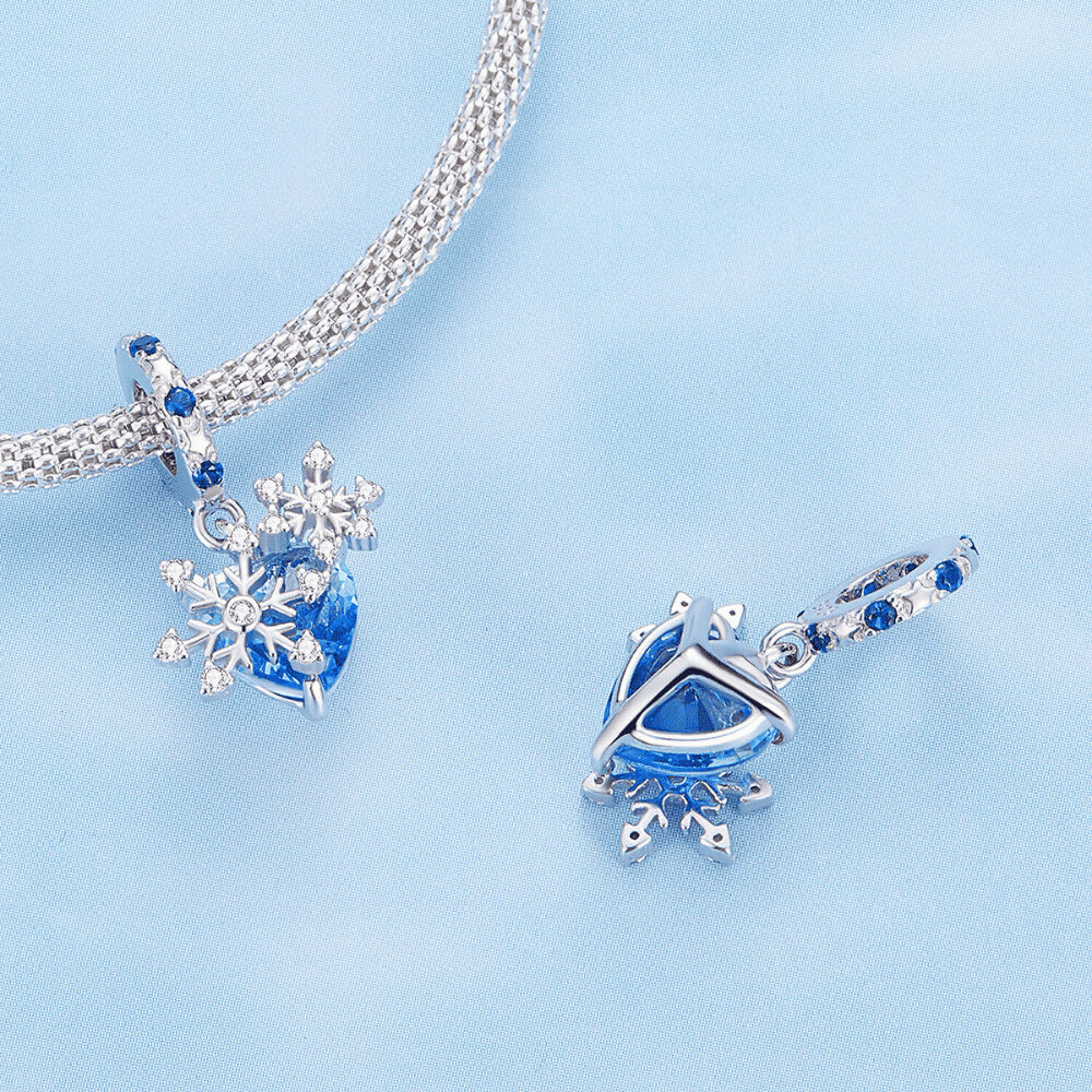 Sterling silver snowflake charm with blue heart crystal and blue gemstone bail.