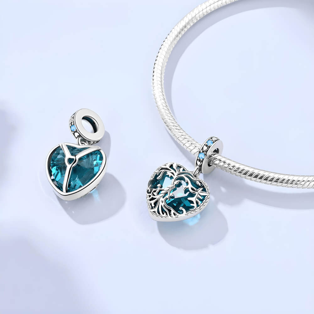 Sterling silver heart charm with intricate vine filigree over a deep blue gemstone and blue crystal accents 