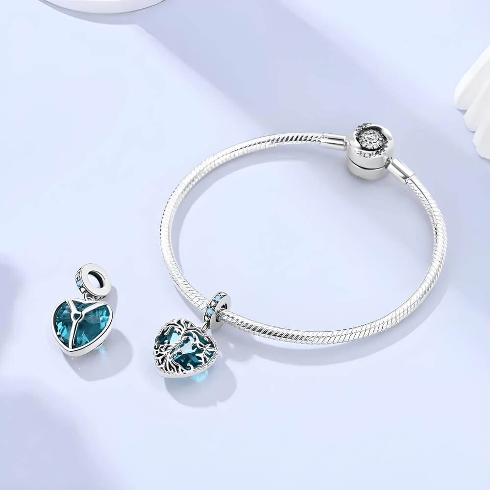 Sterling silver heart charm with intricate vine filigree over a deep blue gemstone and blue crystal accents