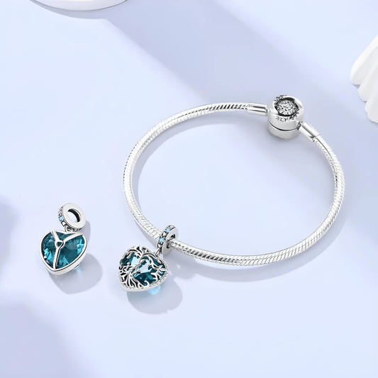 Sterling silver heart charm with intricate vine filigree over a deep blue gemstone and blue crystal accents
