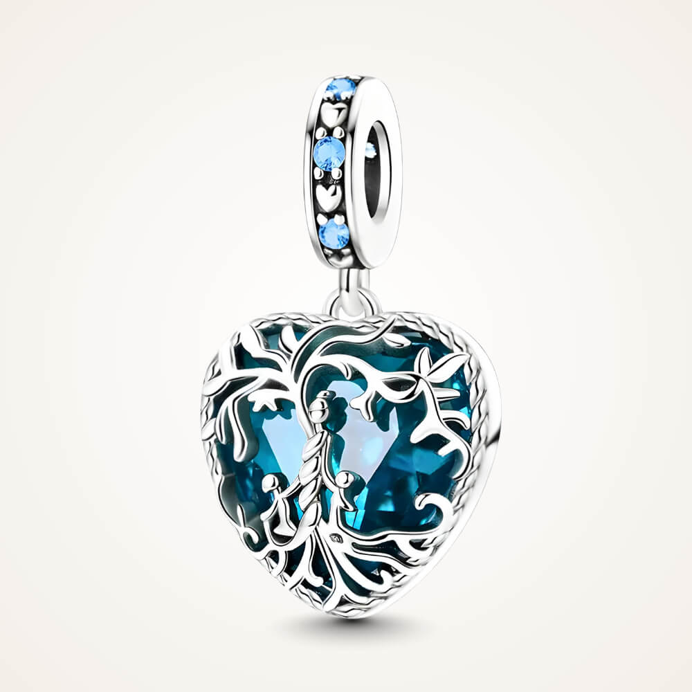 Sterling silver heart charm with intricate vine filigree over a deep blue gemstone and blue crystal accents – ORÉYA.