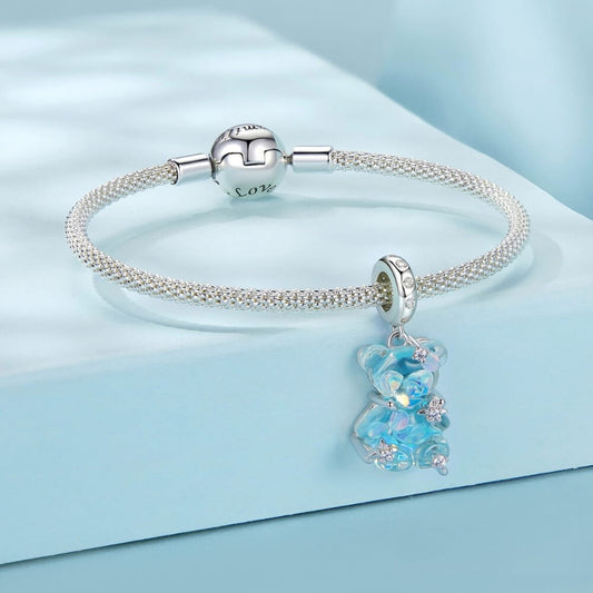Blue teddy bear charm with iridescent finish and sparkling star details.