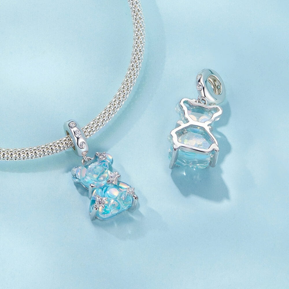 Blue teddy bear charm with iridescent finish and sparkling star details.