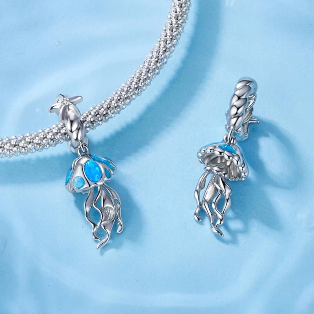 Sterling silver jellyfish charm with blue enamel and flowing ocean details.