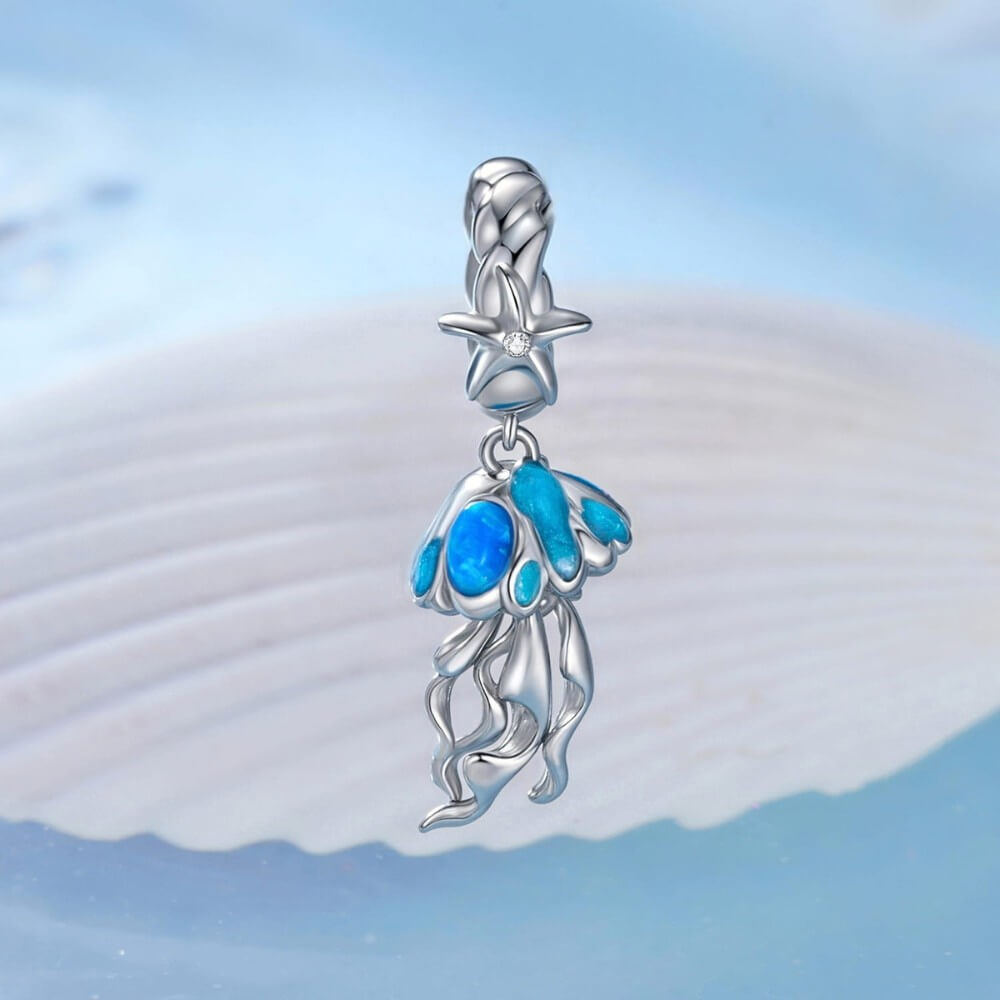 Sterling silver jellyfish charm with blue enamel and flowing ocean details.