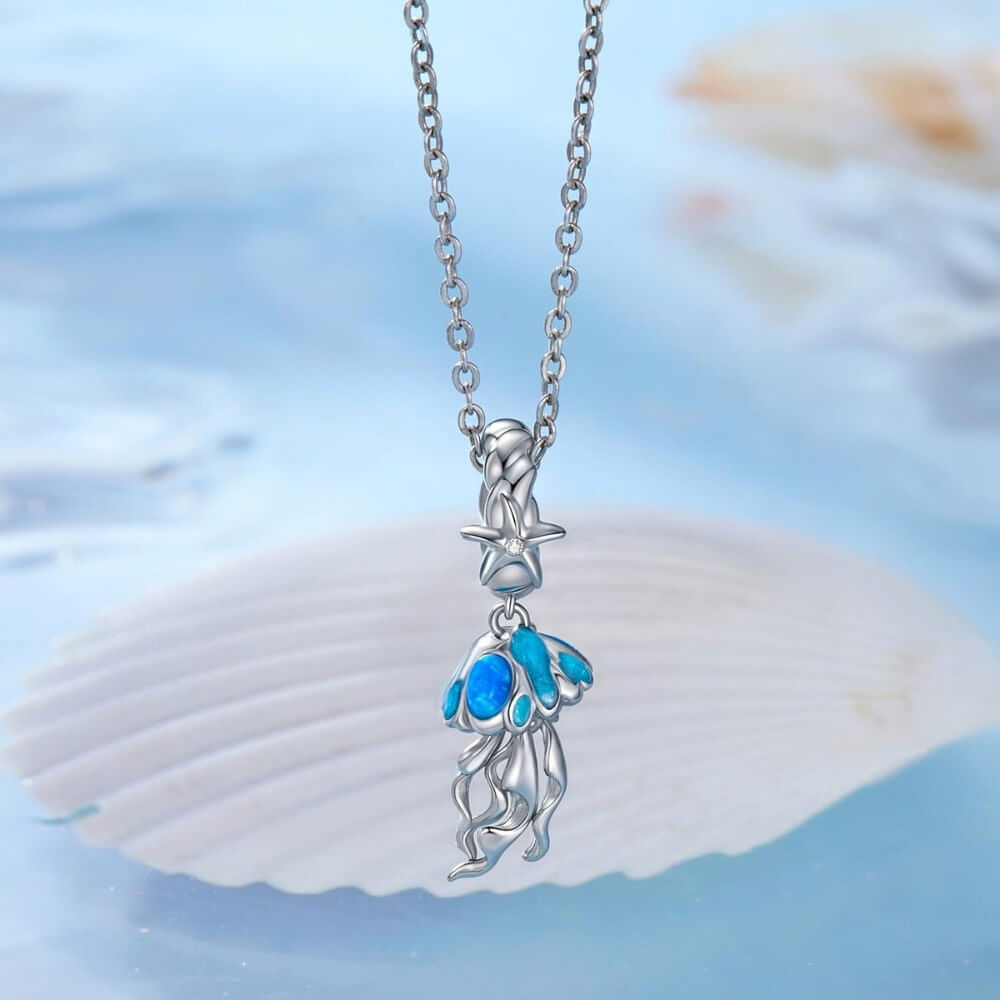 Sterling silver jellyfish charm with blue enamel and flowing ocean details.