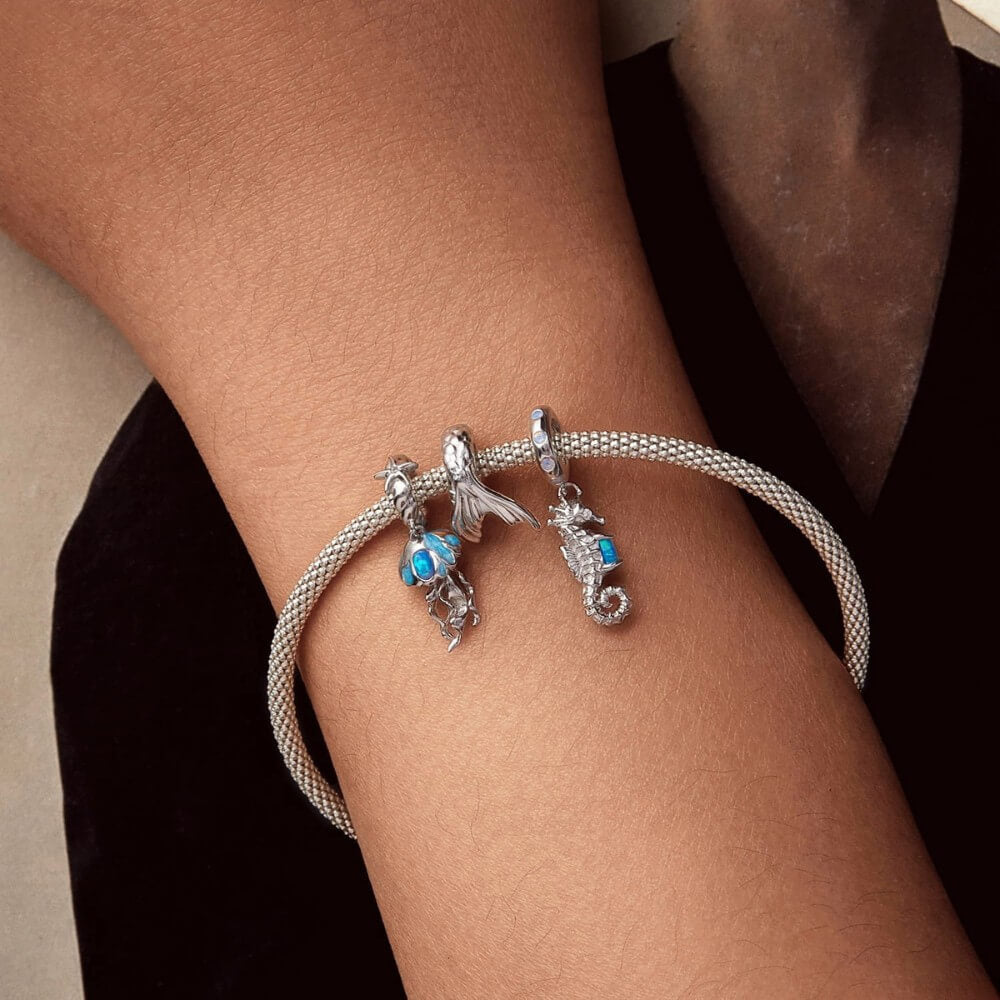 Sterling silver jellyfish charm with blue enamel and flowing ocean details.