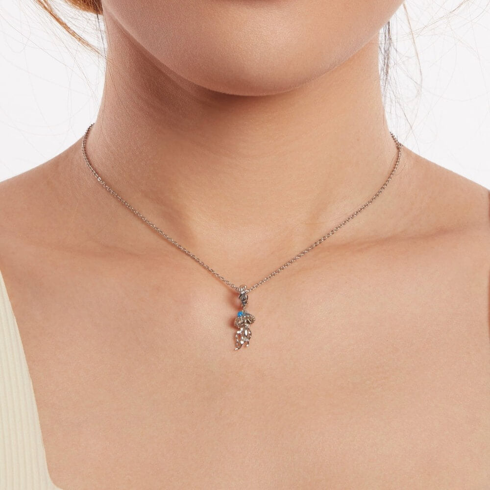 Sterling silver jellyfish charm with blue enamel and flowing ocean details.