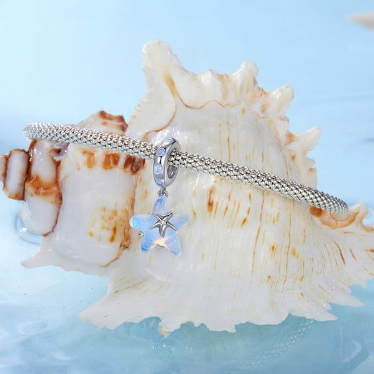 Sterling silver starfish charm with blue opalescent enamel and crystal detail.