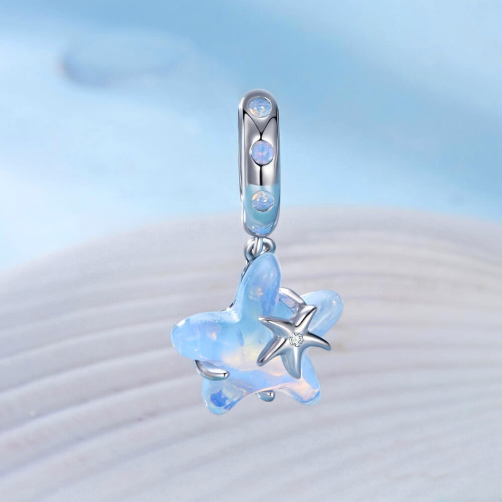 Sterling silver starfish charm with blue opalescent enamel and crystal detail.