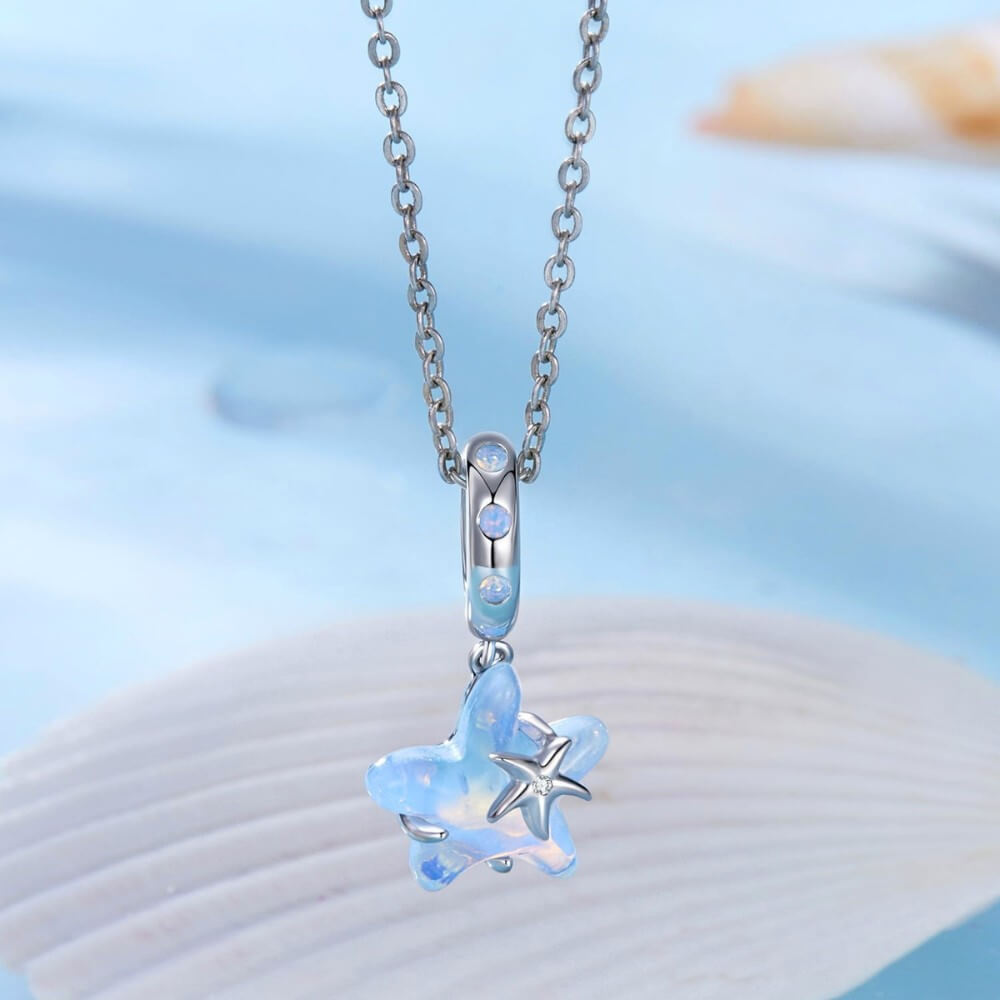 Sterling silver starfish charm with blue opalescent enamel and crystal detail.