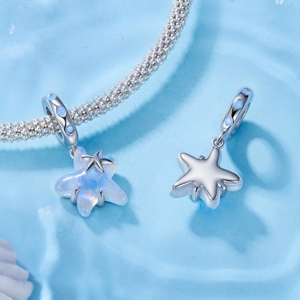 Sterling silver starfish charm with blue opalescent enamel and crystal detail.