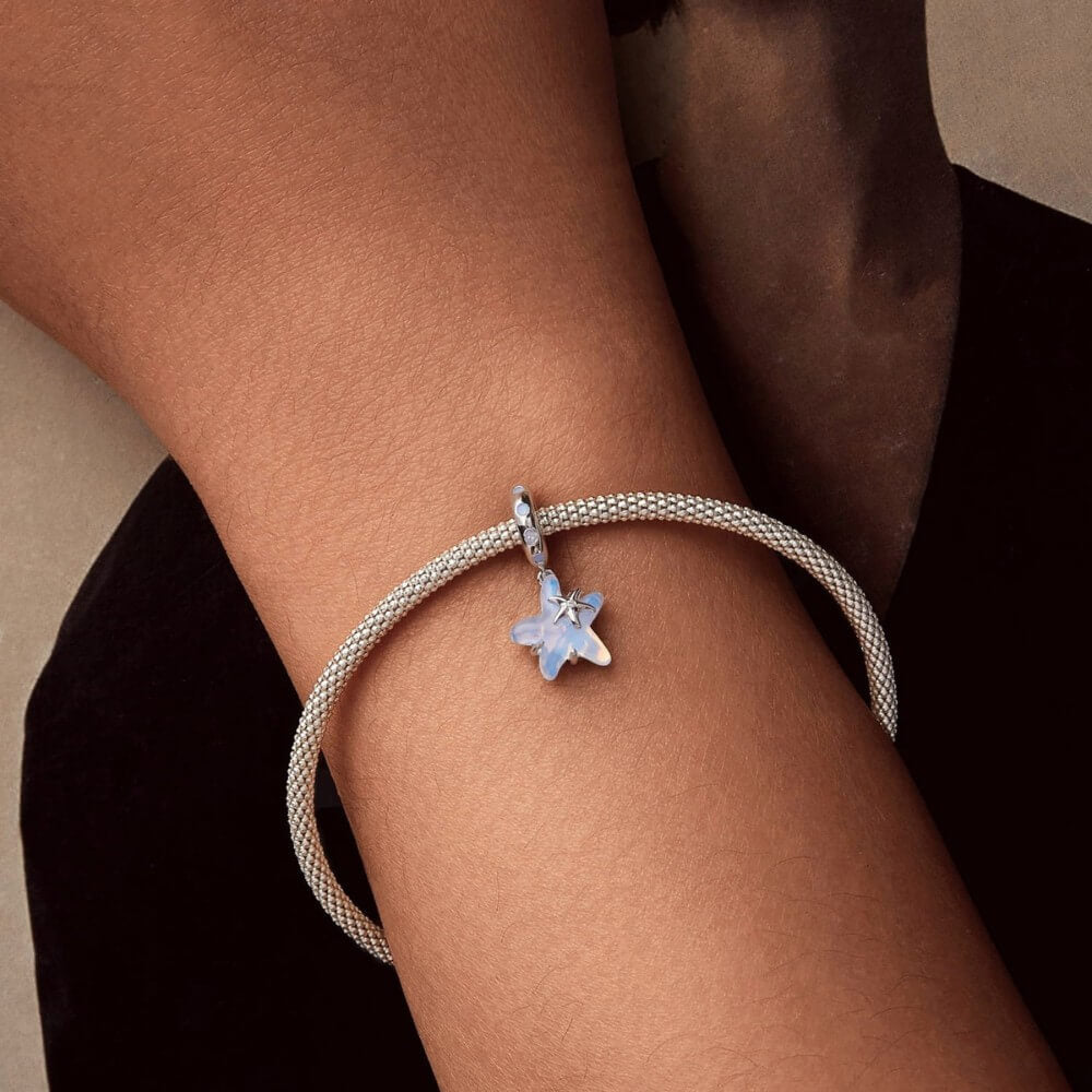 Sterling silver starfish charm with blue opalescent enamel and crystal detail.