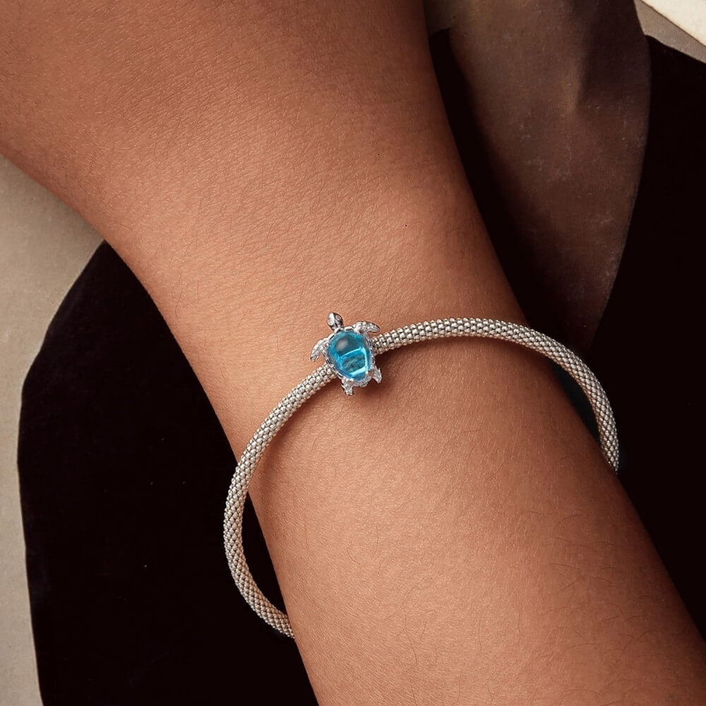 Sterling silver sea turtle charm with blue crystal shell and detailed flippers.