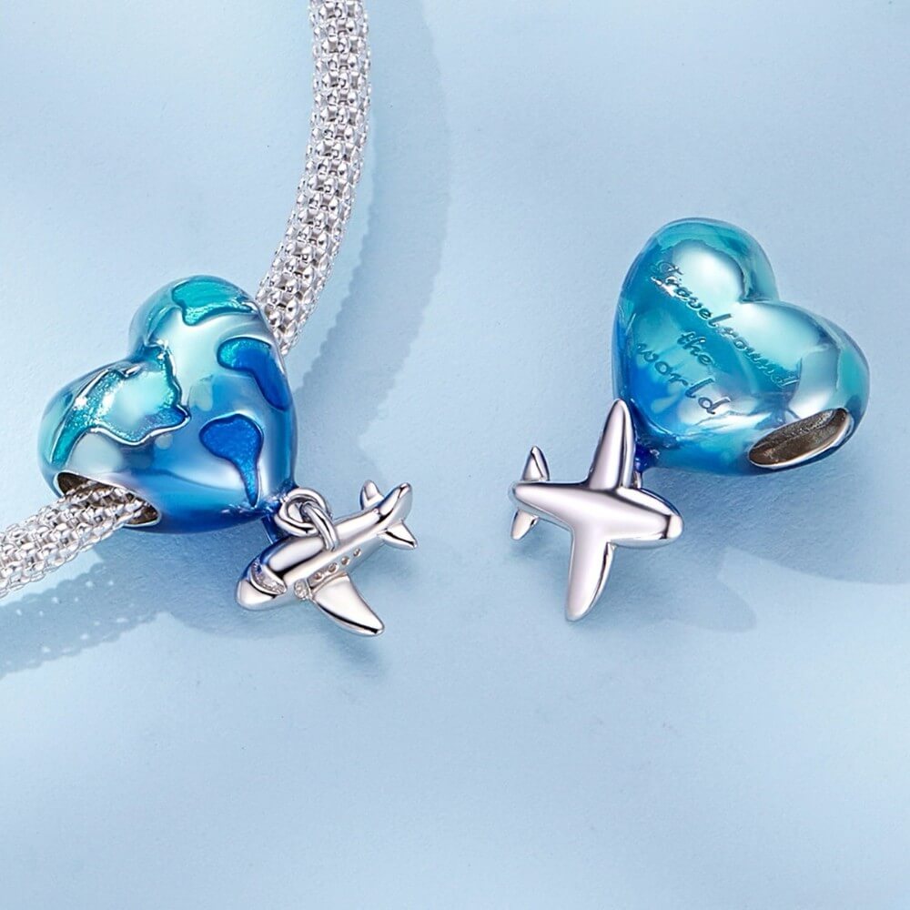 Heart-shaped blue and silver charm with airplane on a light blue background