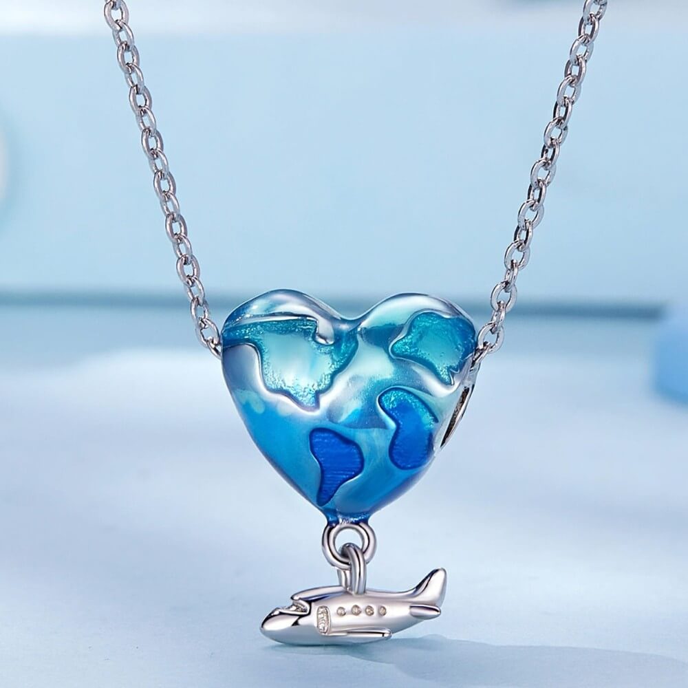 Heart-shaped blue pendant with airplane charm on a light blue background