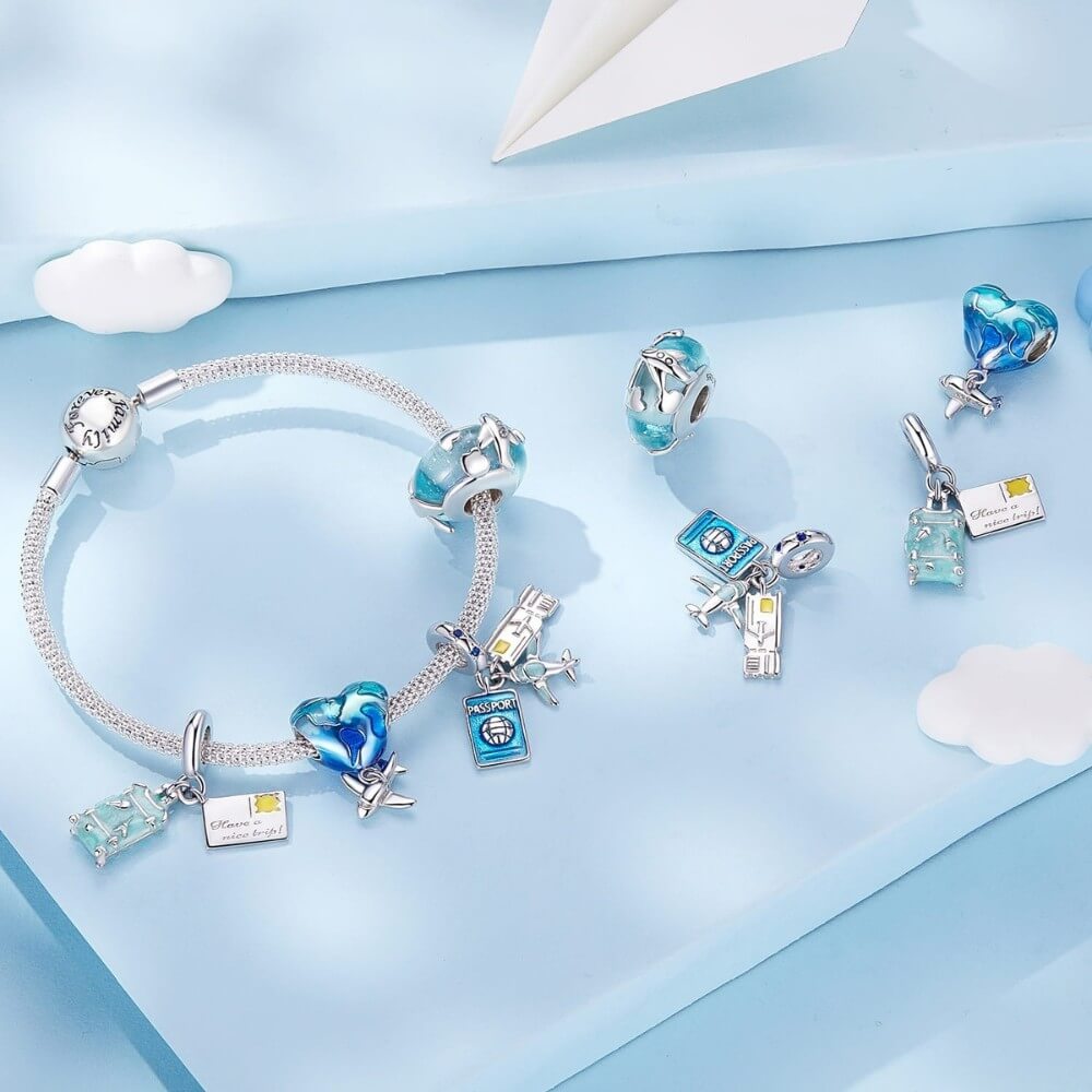 Blue heart travel charm with world map design and silver airplane dangle.