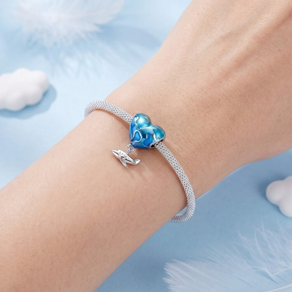 Blue heart travel charm with world map design and silver airplane dangle.