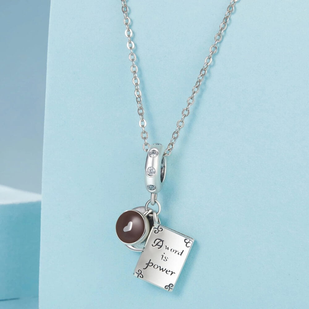 Sterling silver book and coffee charm with engraved inspirational quote.