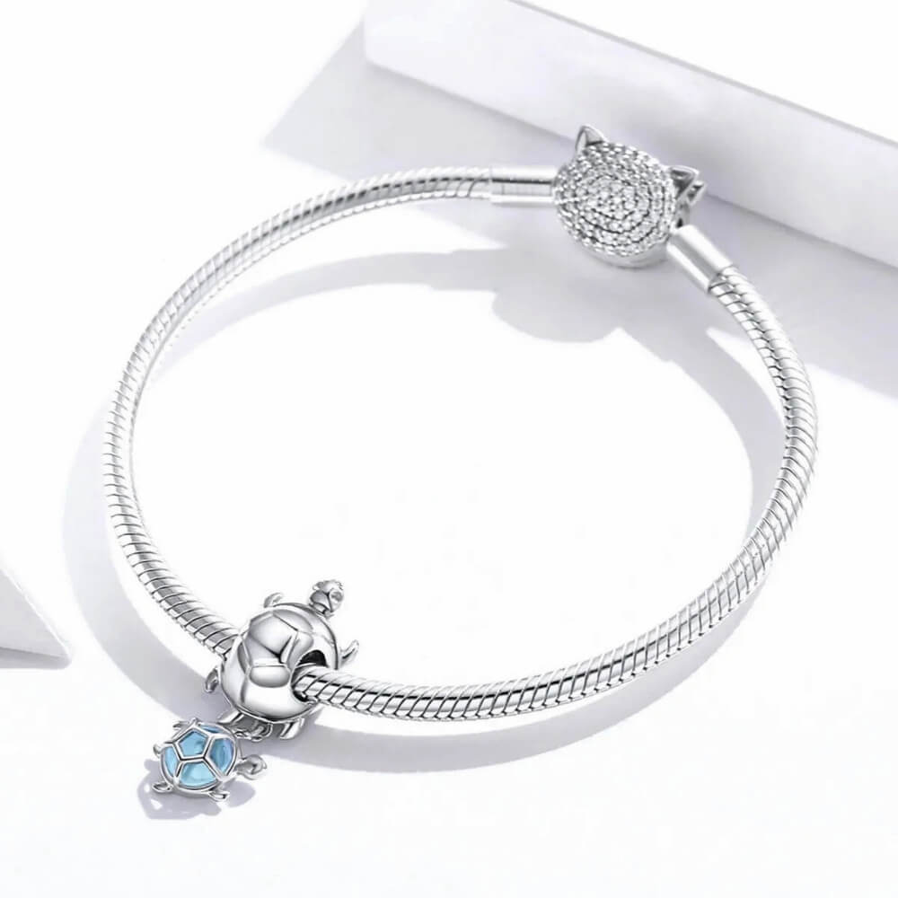 Sterling silver turtle charm with baby turtle detail and soft blue glass accent.