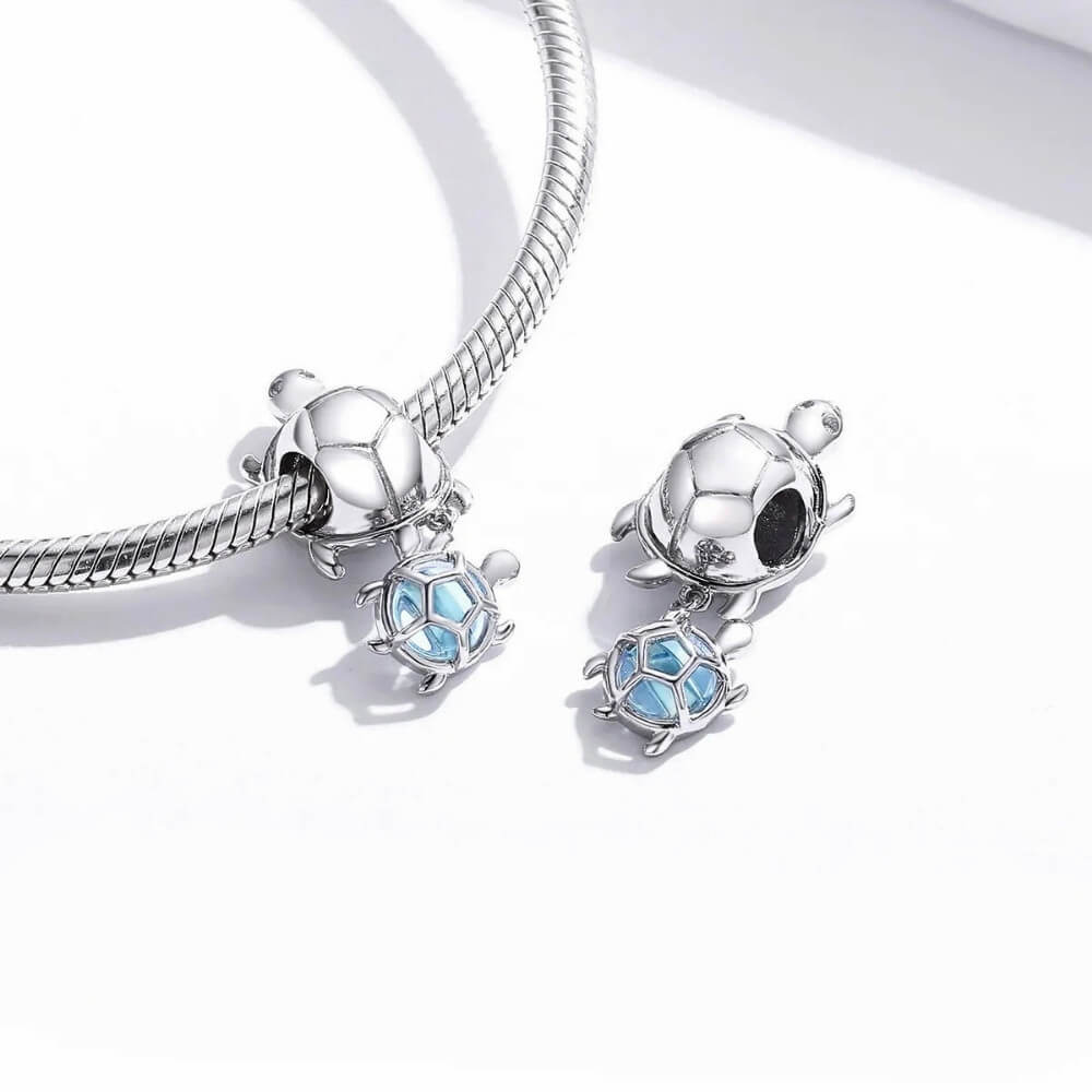 Sterling silver turtle charm with baby turtle detail and soft blue glass accent.