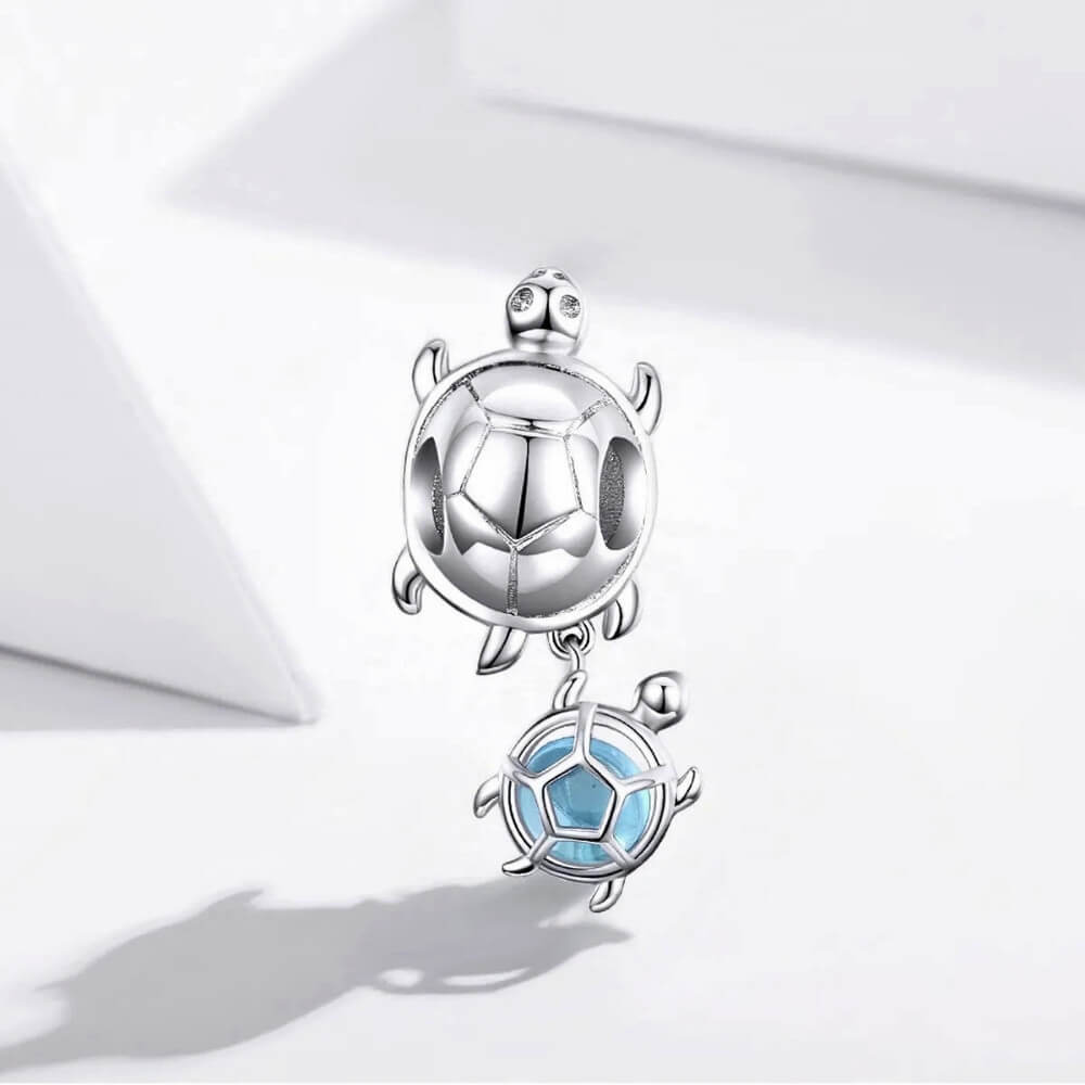 Sterling silver turtle charm with baby turtle detail and soft blue glass accent.