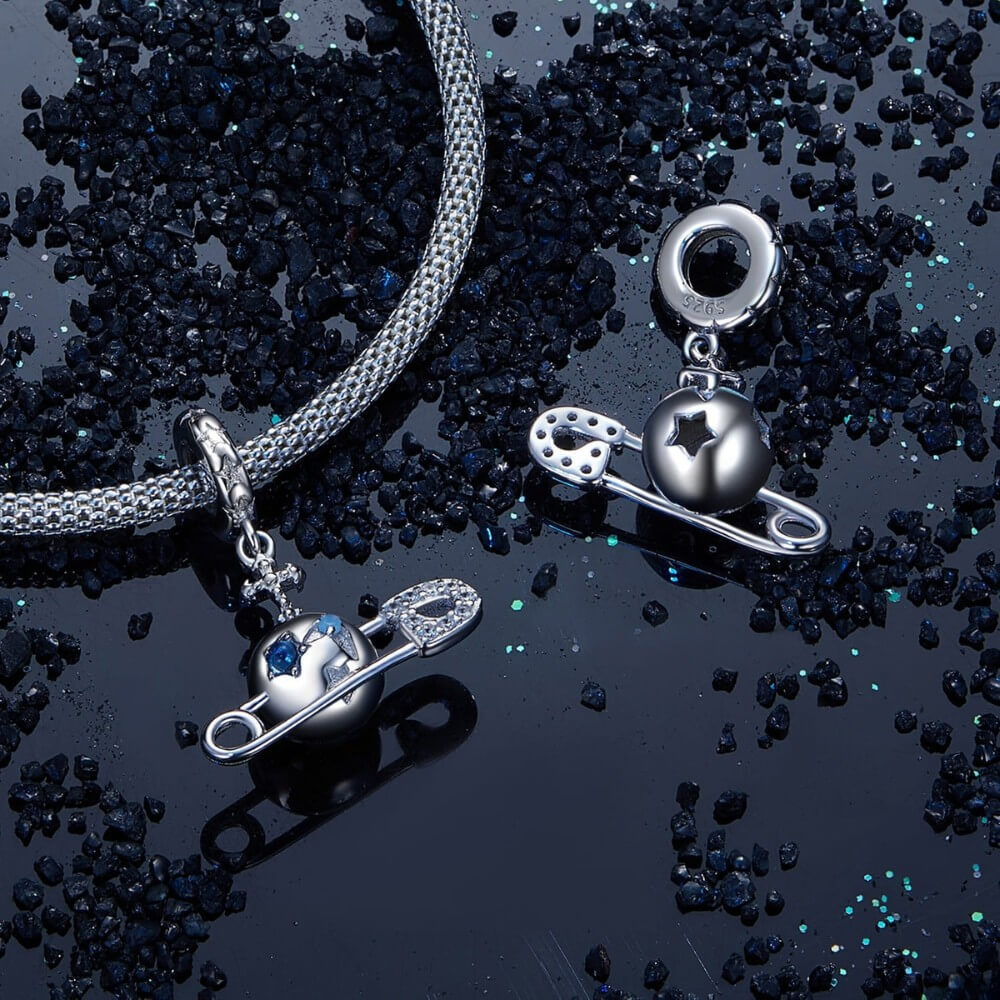 Sterling silver safety pin charm with stars, crystals, and celestial details.