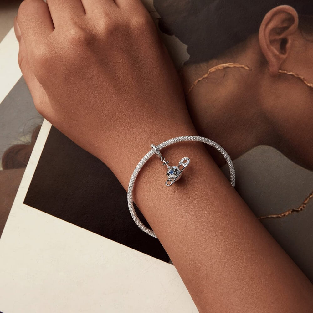 Sterling silver safety pin charm with stars, crystals, and celestial details.