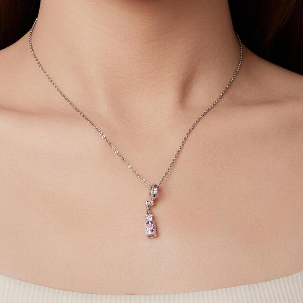 Sterling silver champagne bottle charm with pink enamel, bow detail and heart crystal.