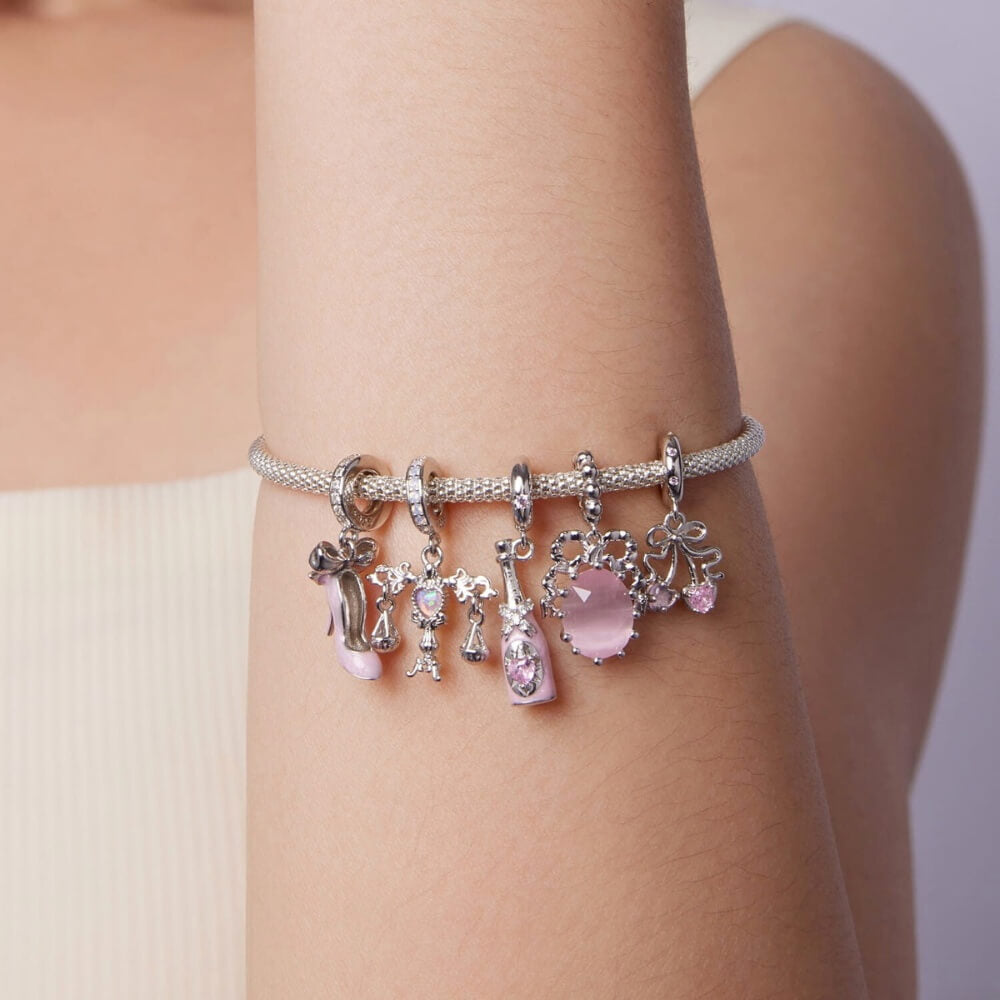Sterling silver champagne bottle charm with pink enamel, bow detail and heart crystal.