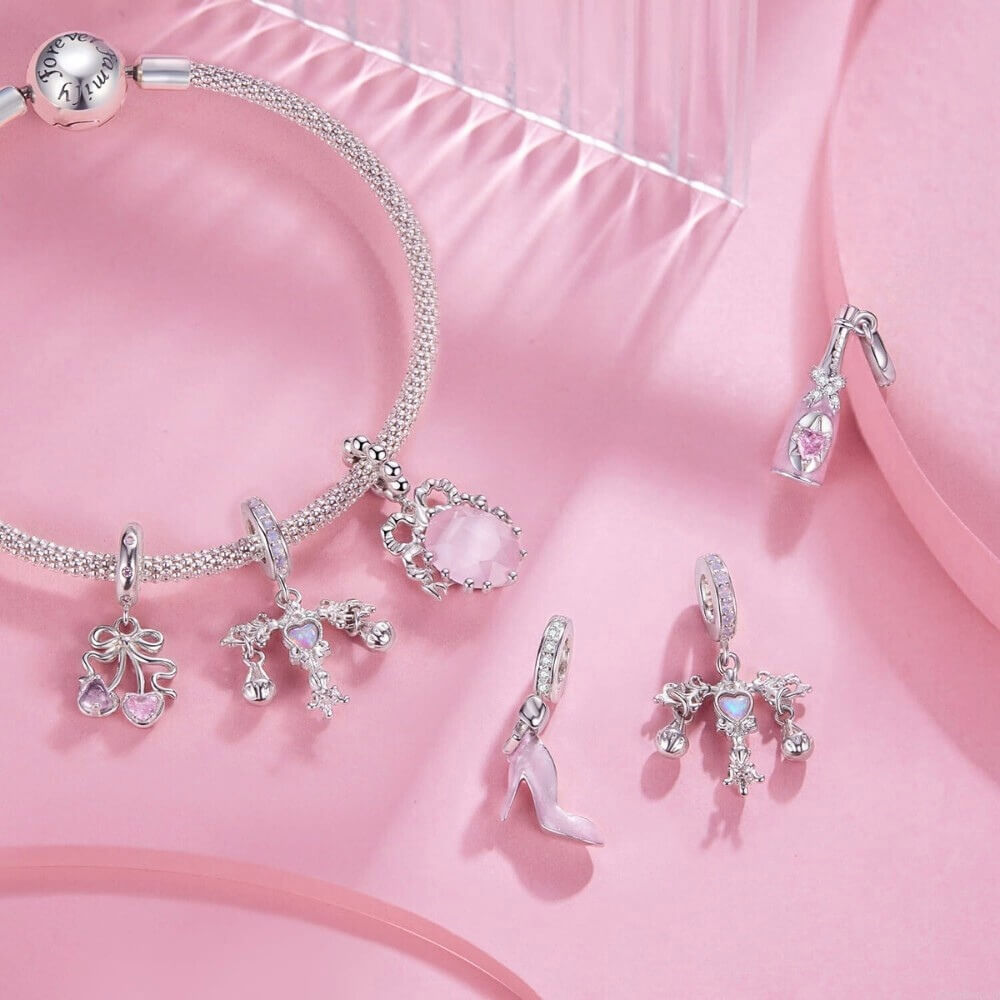 Sterling silver champagne bottle charm with pink enamel, bow detail and heart crystal.