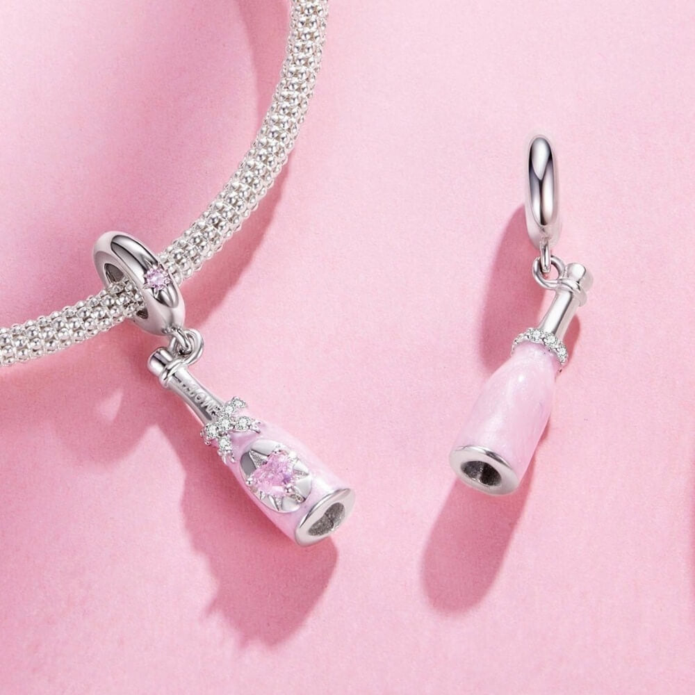 Sterling silver champagne bottle charm with pink enamel, bow detail and heart crystal.