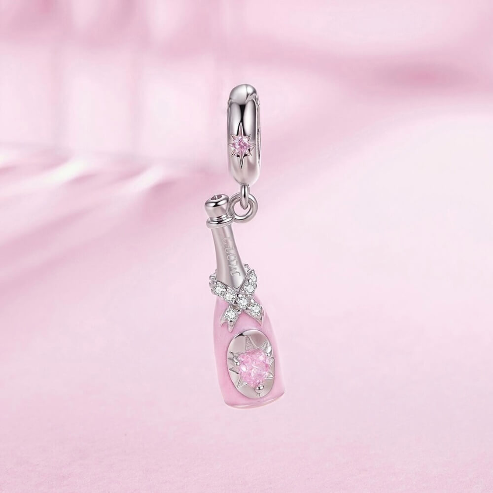 Sterling silver champagne bottle charm with pink enamel, bow detail and heart crystal.