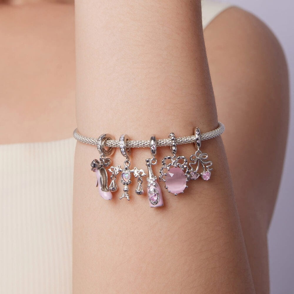 Sterling silver cherry charm with pink heart gemstones and bow detail.