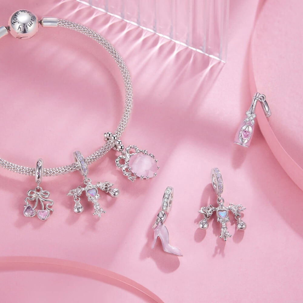 Sterling silver cherry charm with pink heart gemstones and bow detail.