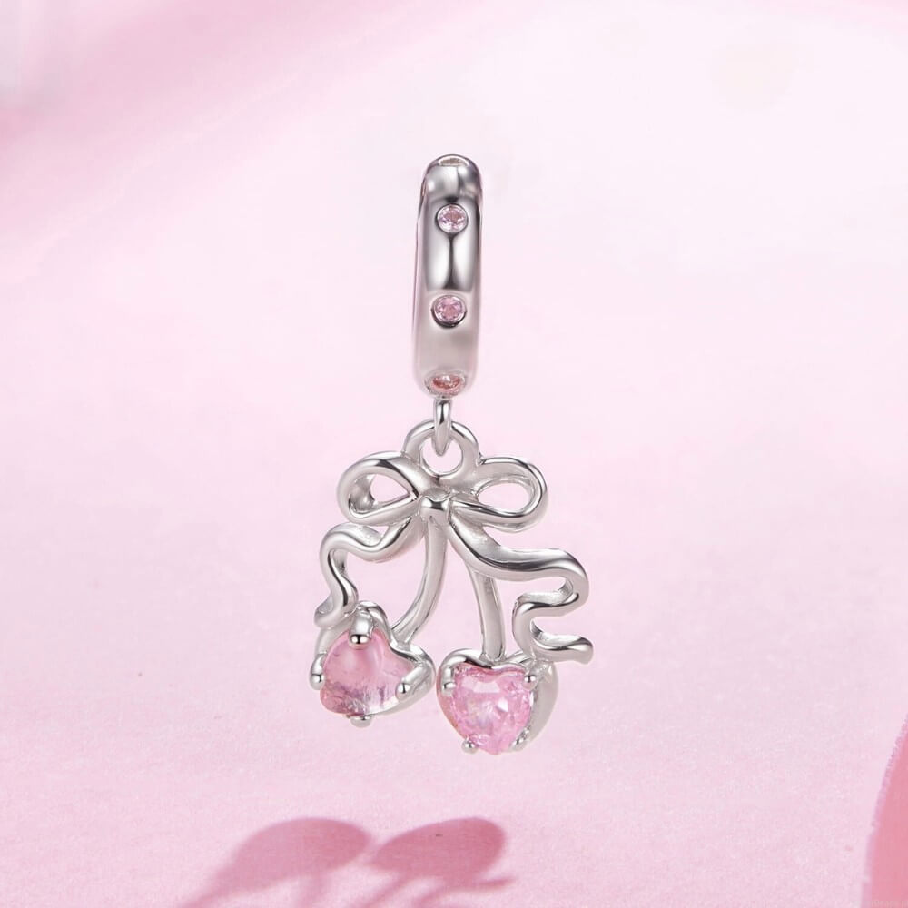 Sterling silver cherry charm with pink heart gemstones and bow detail.
