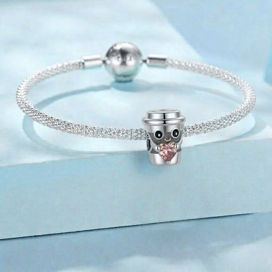 Sterling silver coffee cup charm holding pink heart crystal.