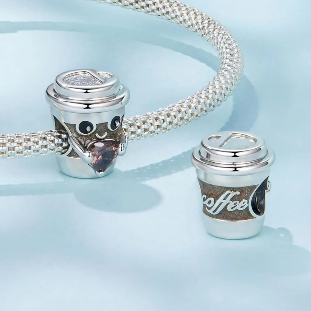 Sterling silver coffee cup charm holding pink heart crystal.