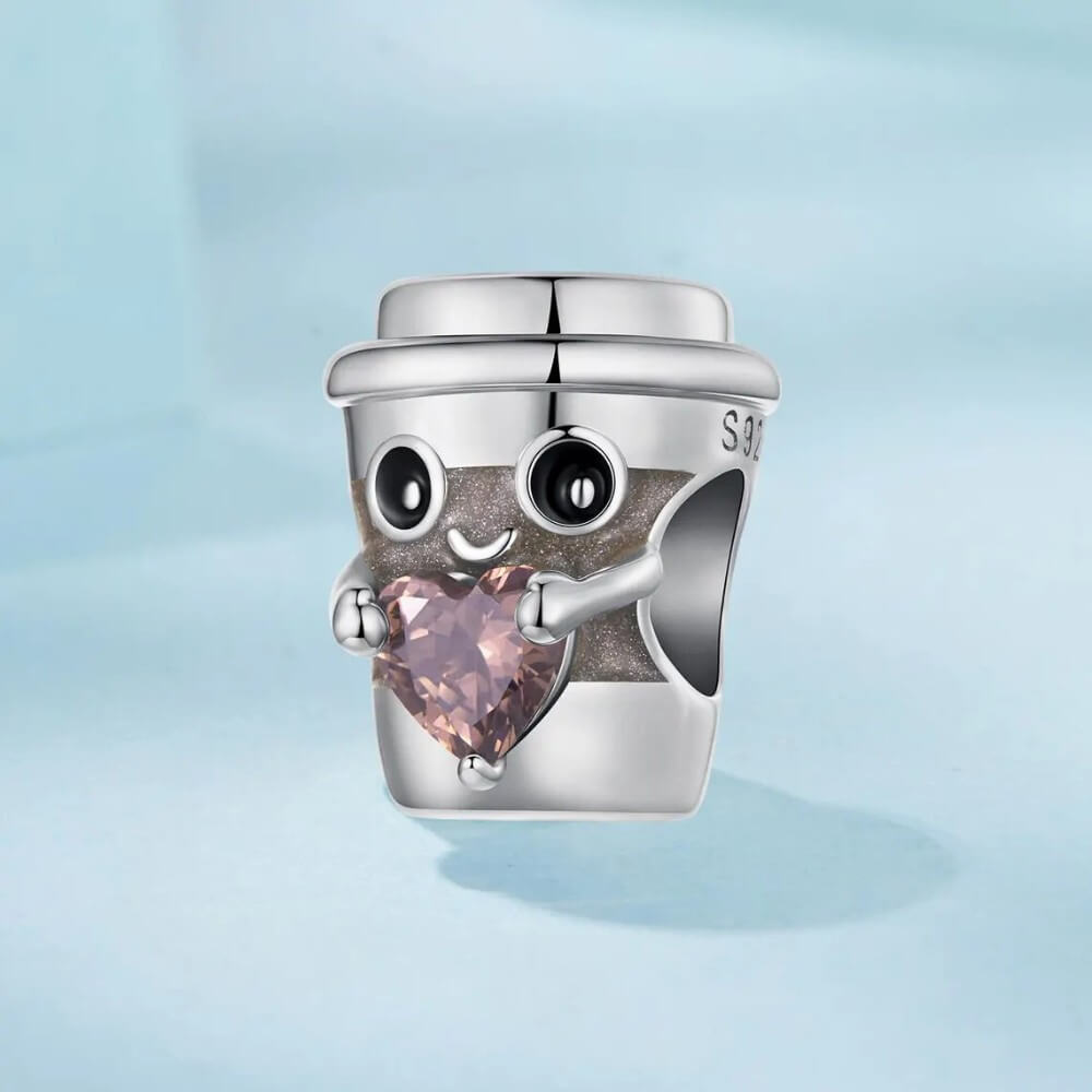 Sterling silver coffee cup charm holding pink heart crystal.